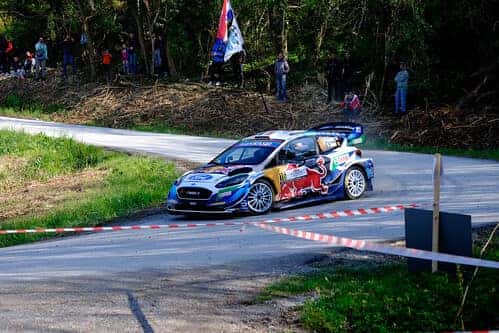 Red Bull branded street racing car turning a tight corner on a downhill track.