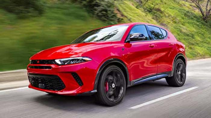 Red Dodge Hornet driving on the road