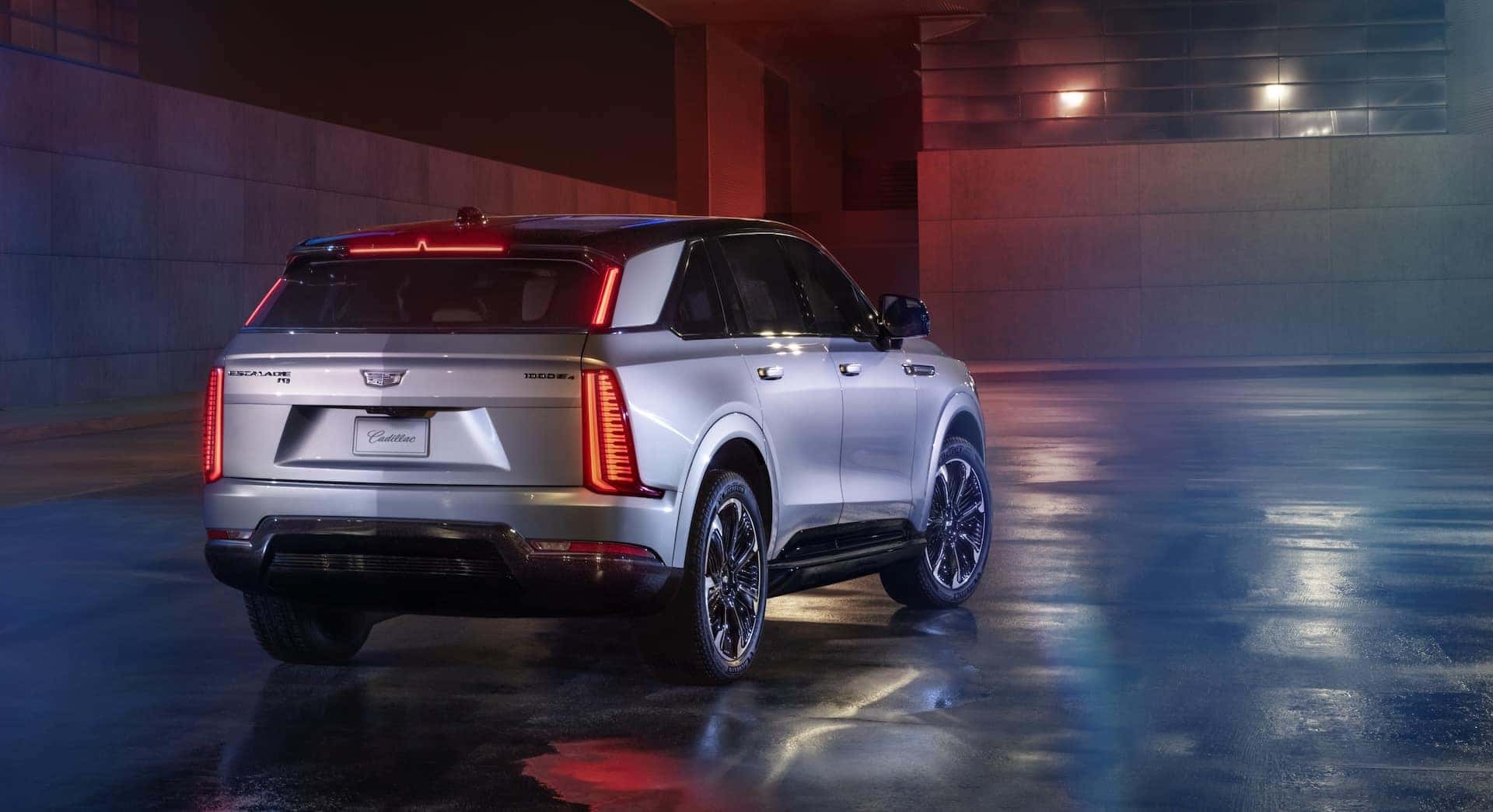 Rear 7/8 view of 2025 Cadillac ESCALADE IQ Sport in Flare Metallic at night.