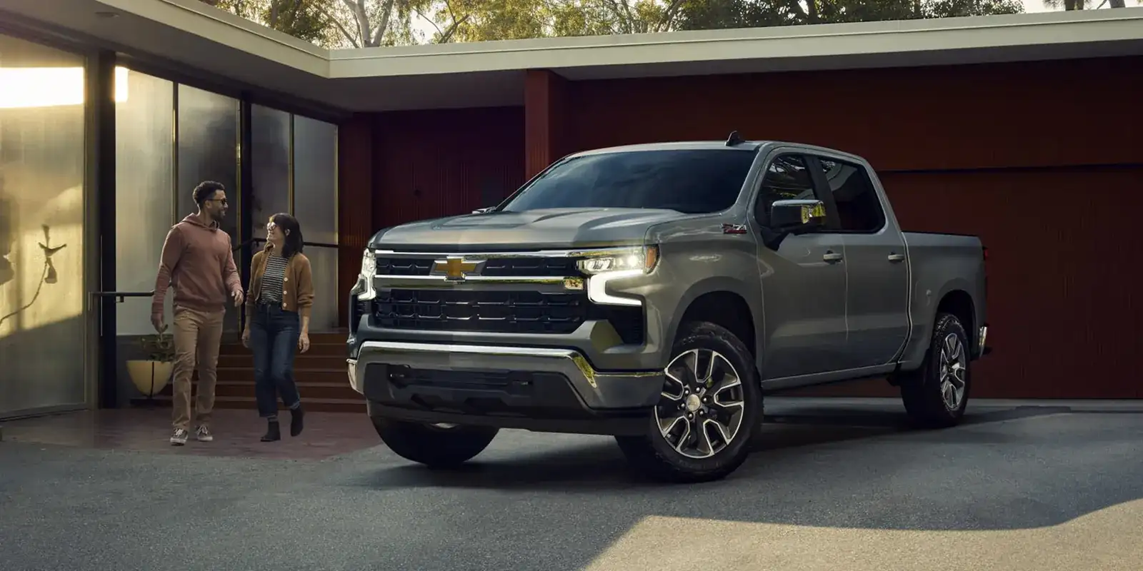 2026 Chevrolet Silverado 1500 parked in front of a modern home with a couple walking by