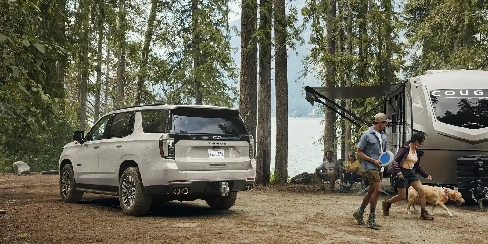 2027 Chevrolet Tahoe with a travel trailer at a forest campsite