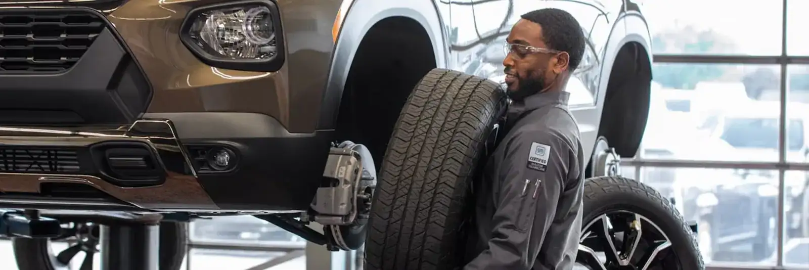 Chevrolet Certified Service technician mounting a tire on a vehicle on a service lift