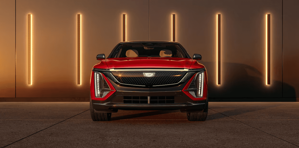 A Radiant Red Metallic 2024 Cadillac Lyriq is shown parked in front of a backlit wall