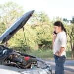 Woman standing near overheated car