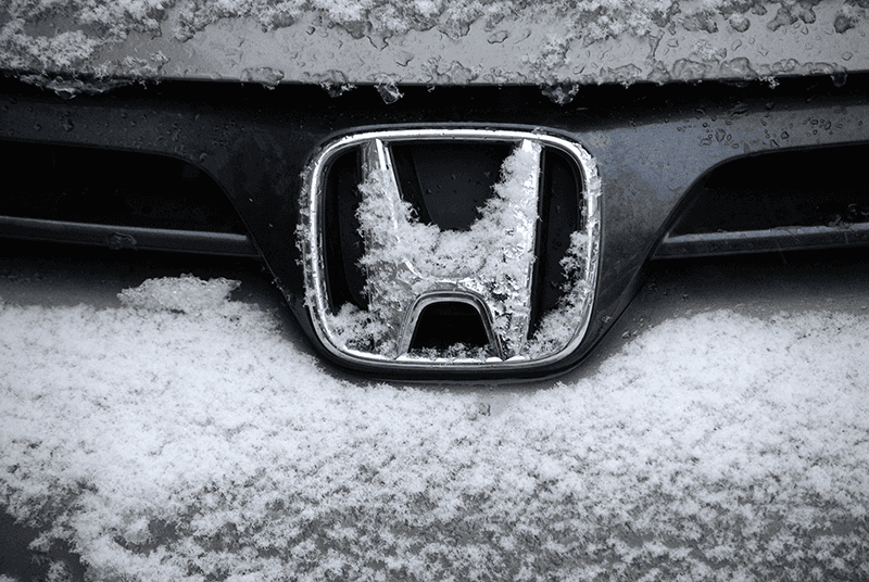 Snow on the Honda Logo on the grill of a vehicle