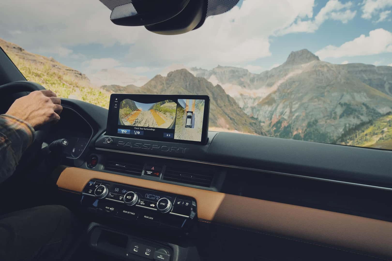 2026 Honda Passport interior cockpit showing infotainment screen with navigation map, tan leather-trimmed dashboard, and mountain vista through windshield