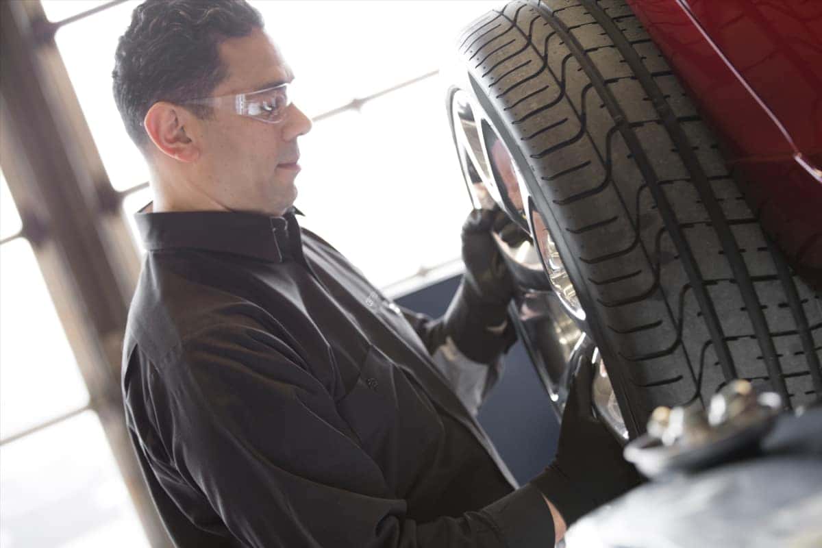 Service technician inspecting a vehicle wheel and brake components at Greg Hubler Buick GMC