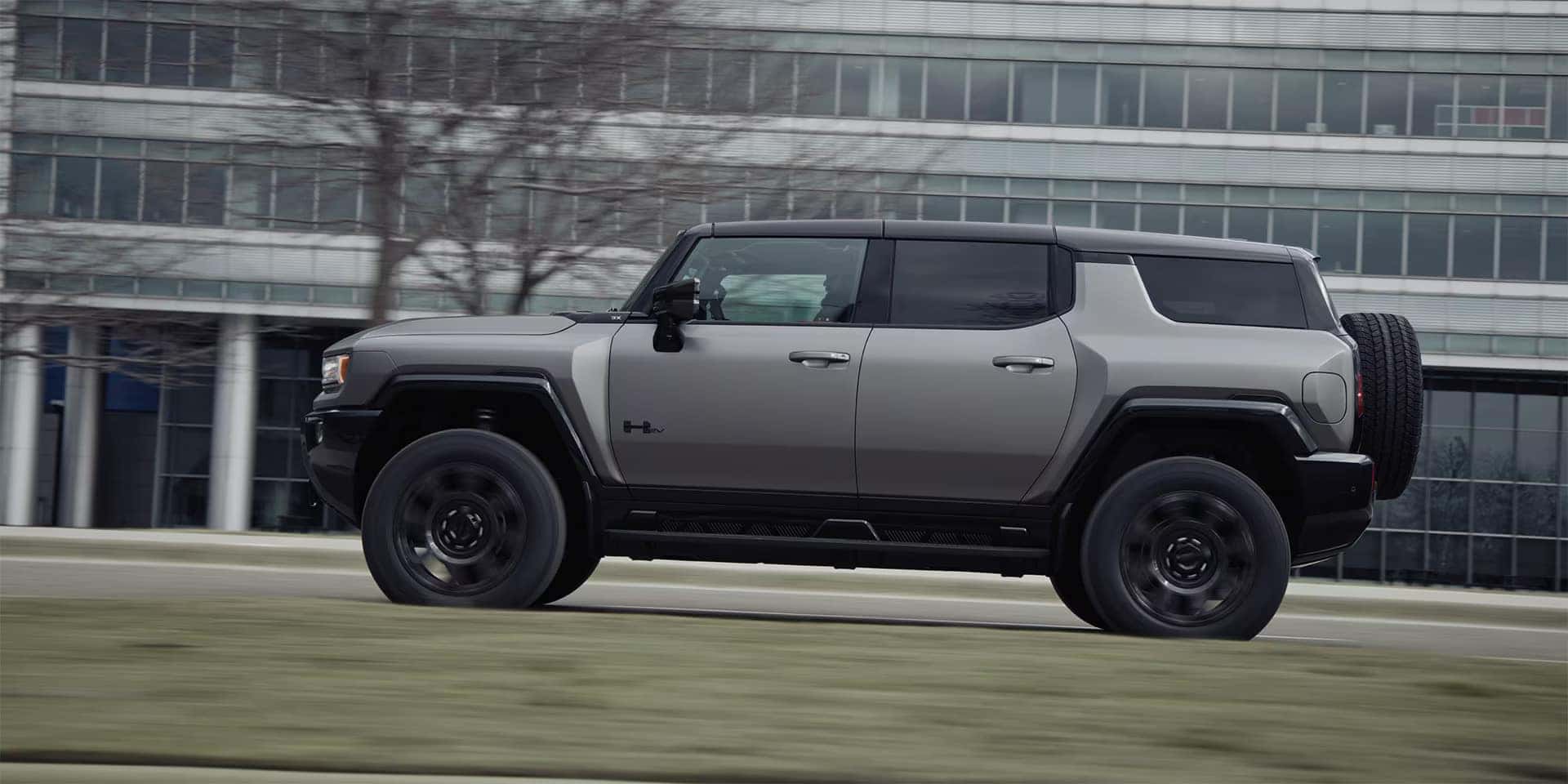 A gray hummer ev suv driving on the road.