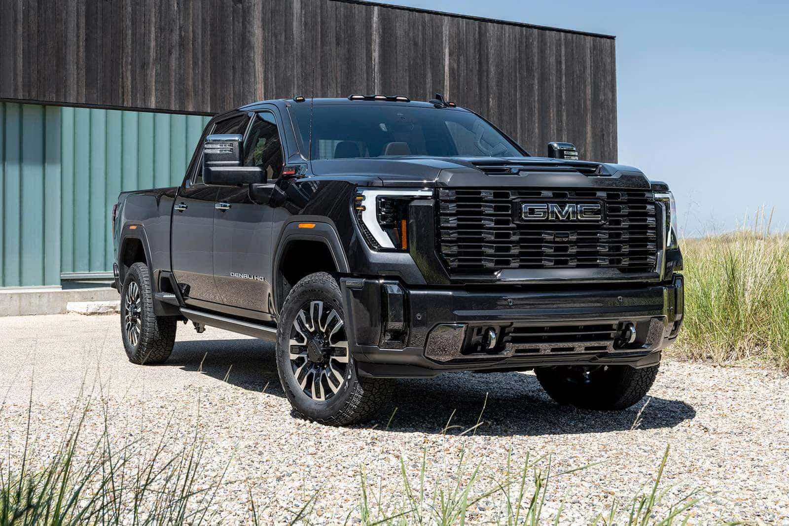 A gmc sierra 3500hd sitting paked on a gravel road.