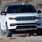 2025 Jeep Grand wagoneer driving up a hill on a farm