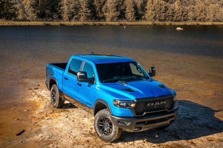 Ram 1500 Rebel in Hydro Blue and Diamond Black parked near a rocky riverbank
