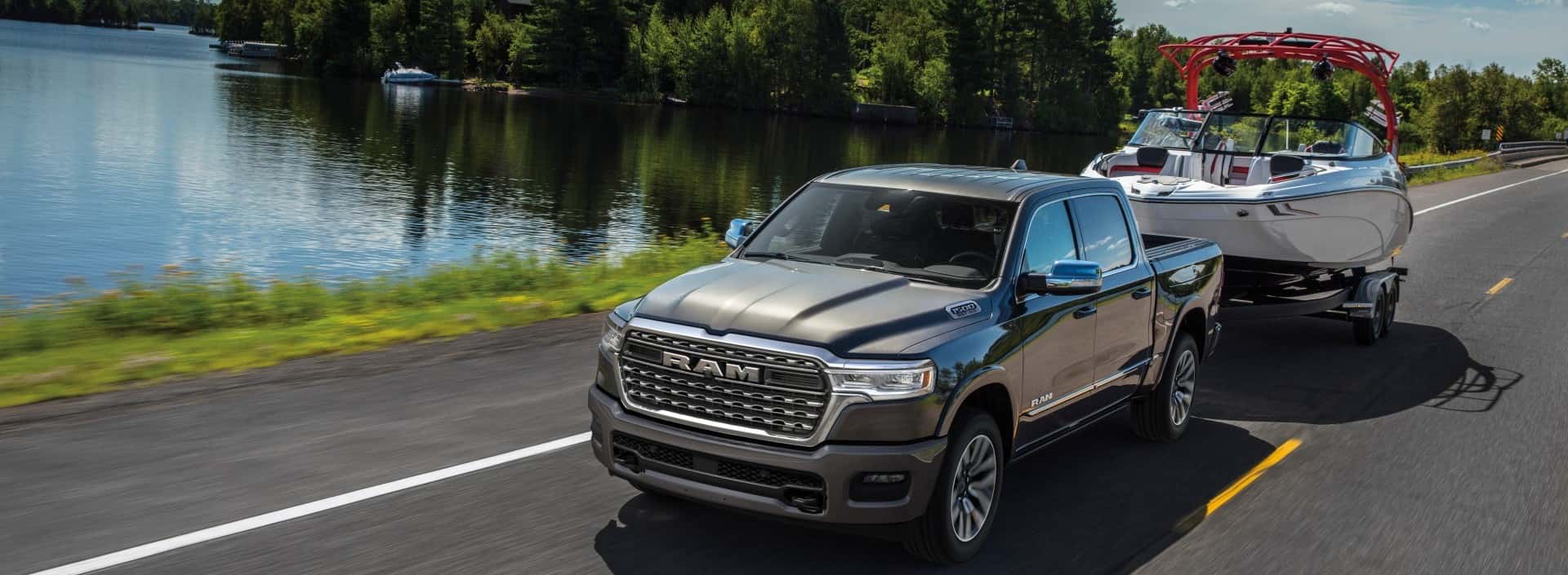 1500 Limited in Billet Silver towing a boat and driving down a tree lined road next to a lake.