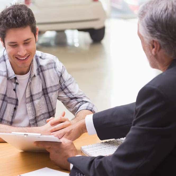 Customer signing a vehicle finance agreement at a dealership