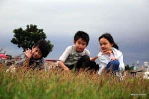 Three siblings sit on a hill at an outdoor destination for families in Marion, Illinois