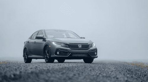 Gray Honda sedan in foggy weather driving on pavement.