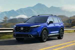 2025 Honda CR-V Hybrid in blue paint driving along a mountainside highway.