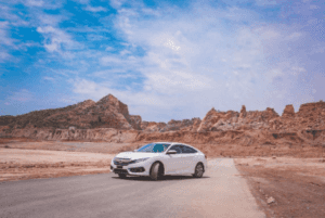 Wide shot of a white Honda civic parked in a desert environment.