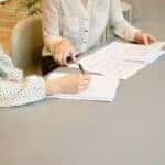 people signing paperwork at a car dealership