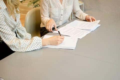people signing paperwork at a car dealership