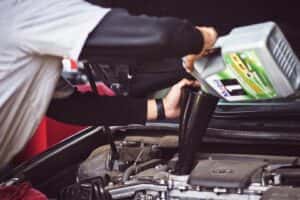 mechanic adding engine oil to a car's engine