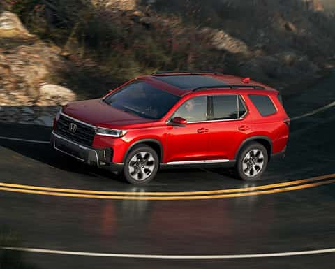red 2026 Honda Pilot SUV driving down the road