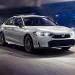 white 2026 Honda Civic Hybrid driving down the road