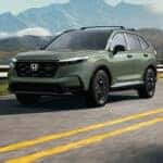 green 2027 Honda CR-V crossover driving down the road