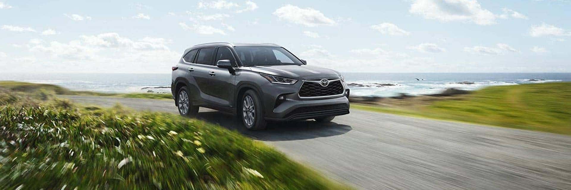 2025 toyota highlander driving on road next to water