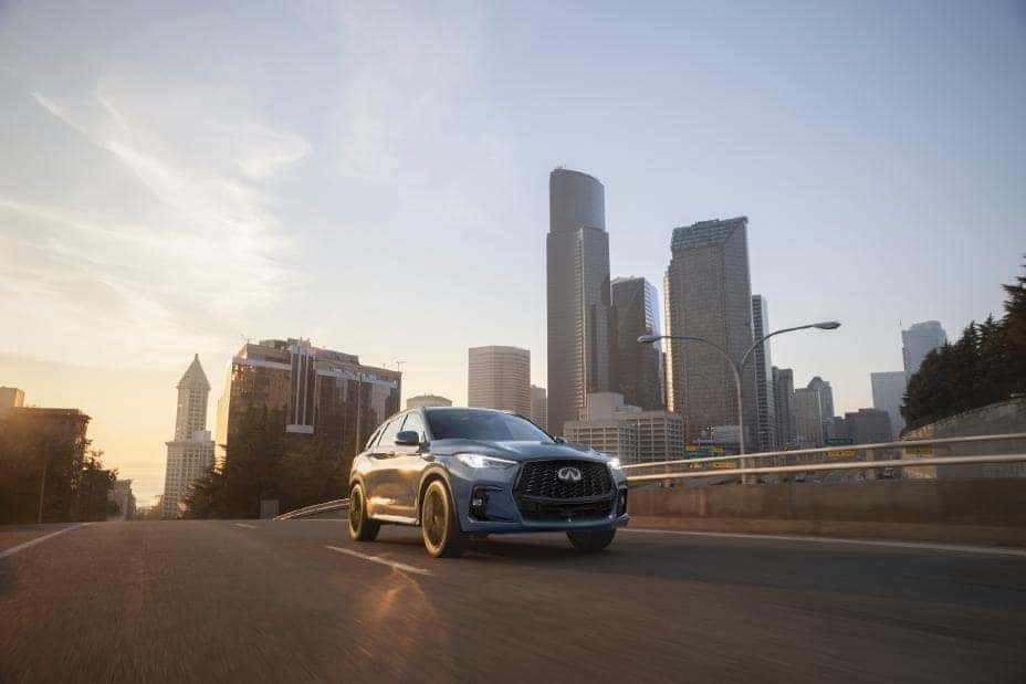 2025 INFINITI QX50 SUV Driving Down Highway with City in Background