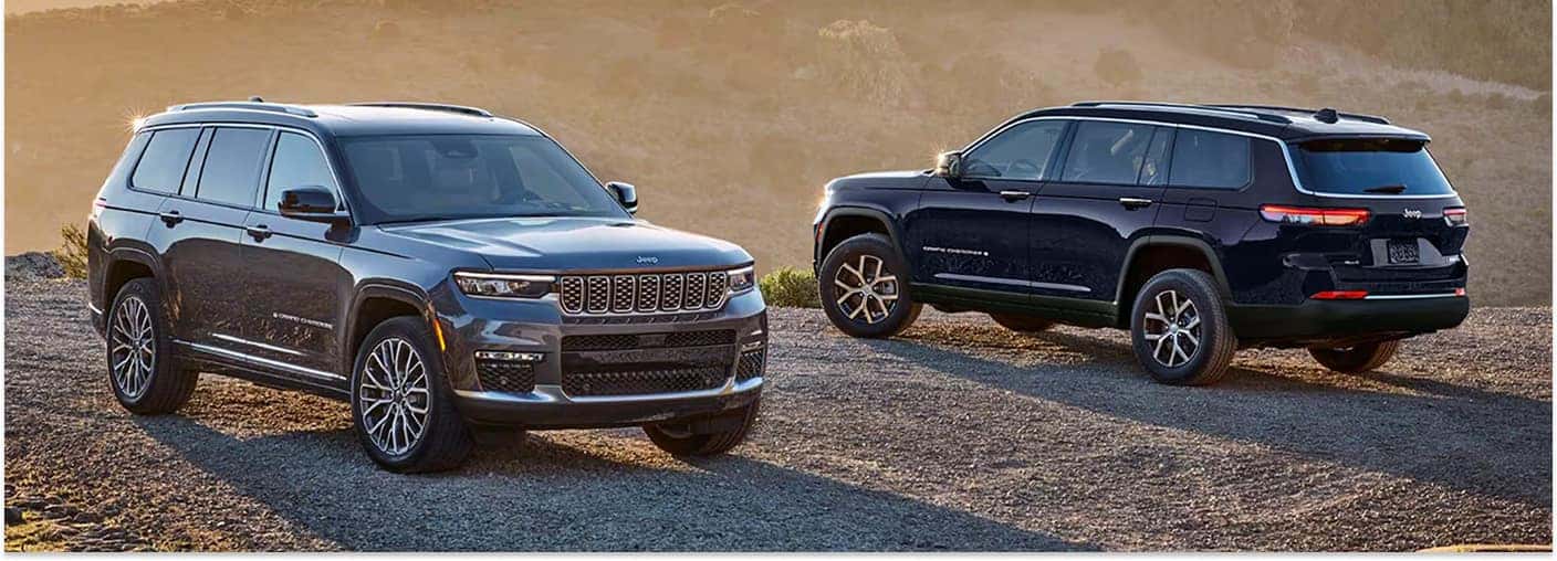 Front and rear profile views of two 2026 Jeep Grand Cherokee SUVs parked on a dirt road outdoors.