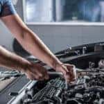 Auto mechanic working on car engine
