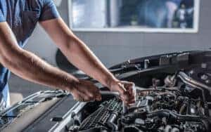 Auto mechanic working on car engine