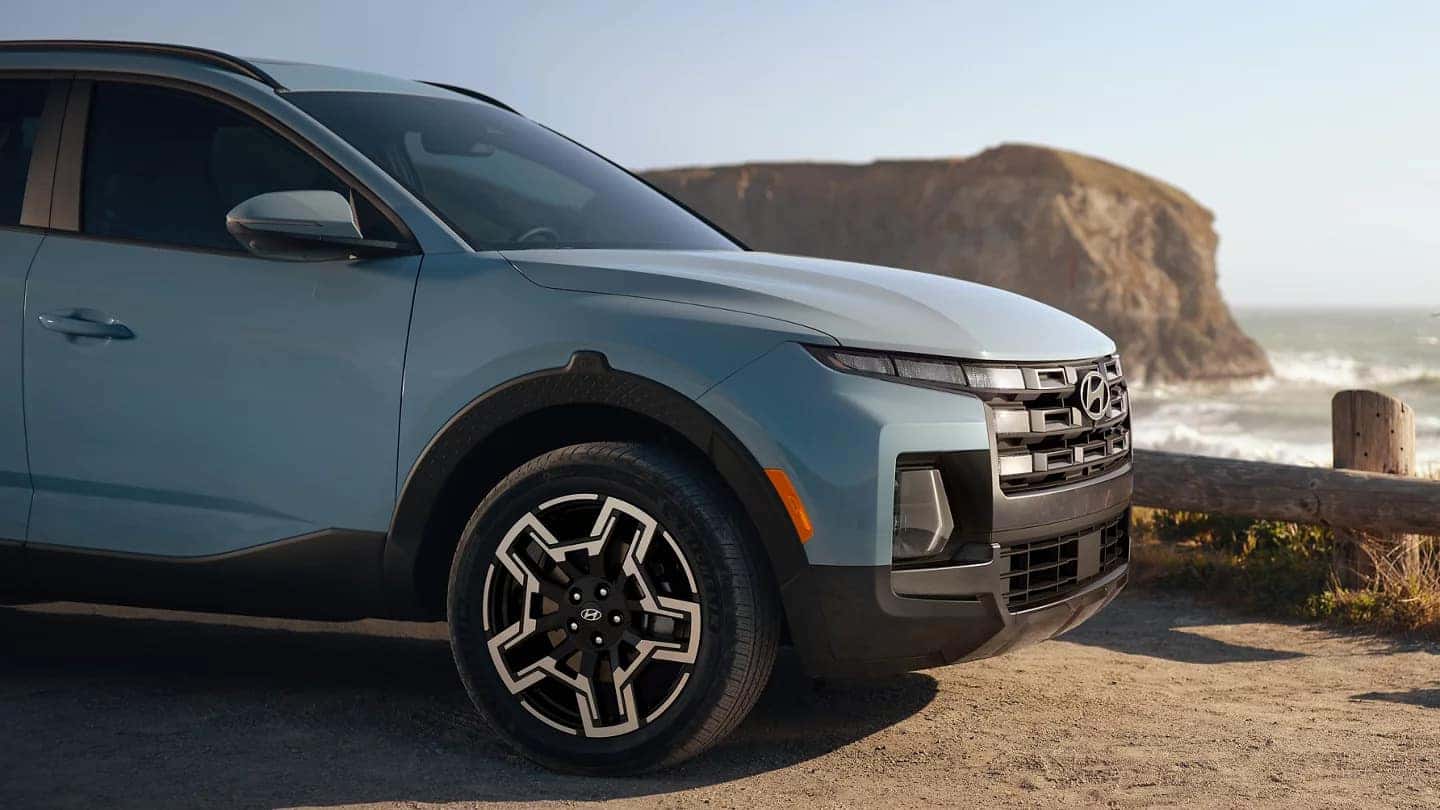 A light blue Hyundai Santa Cruz parked on a dirt road over a cliffside