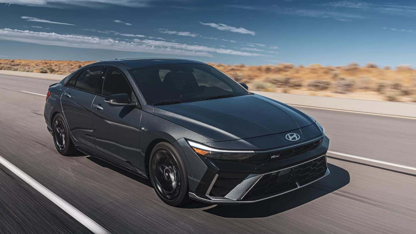 A black Hyundai Elantra driving down the road through a desert