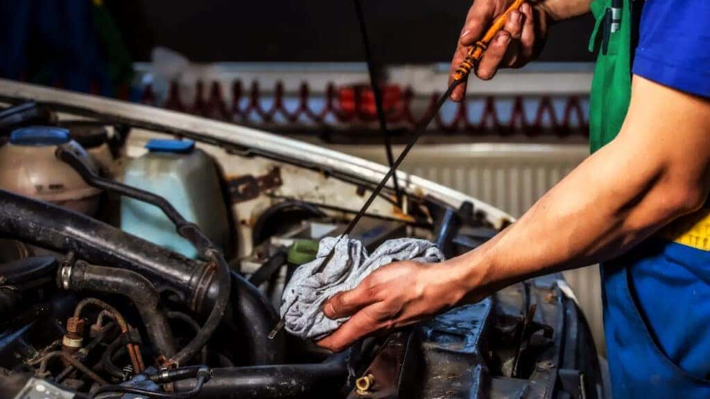 A technician checking engine oil level