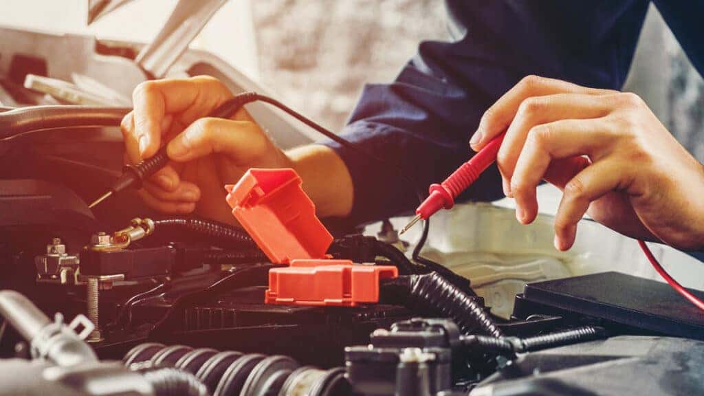 A technician testing a vehicle's battery