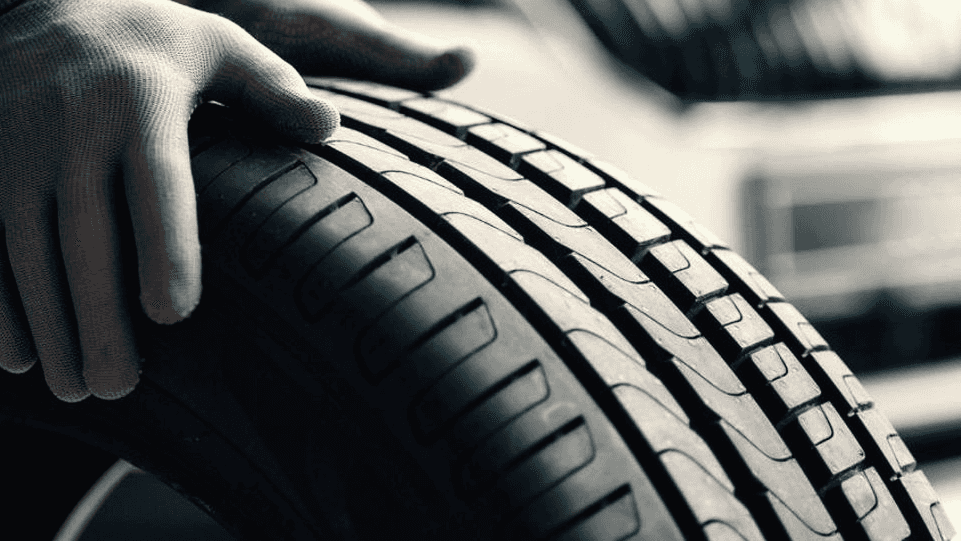 A technician moving a vehicle's tire