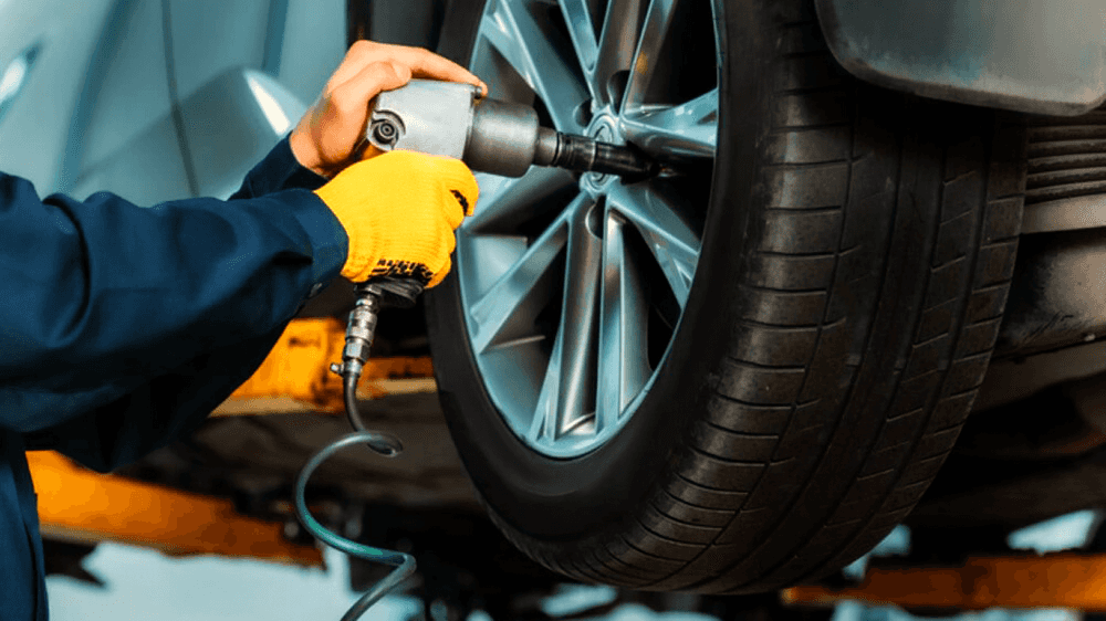A technician performing a tire rotation on a vehicle