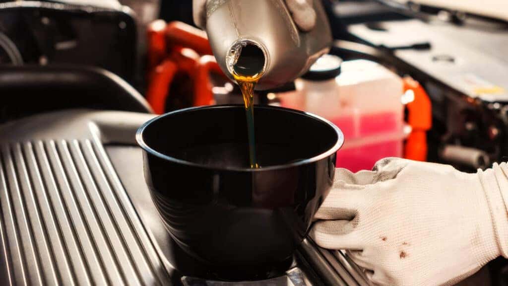 Clean engine oil being poured as part of a regular oil change
