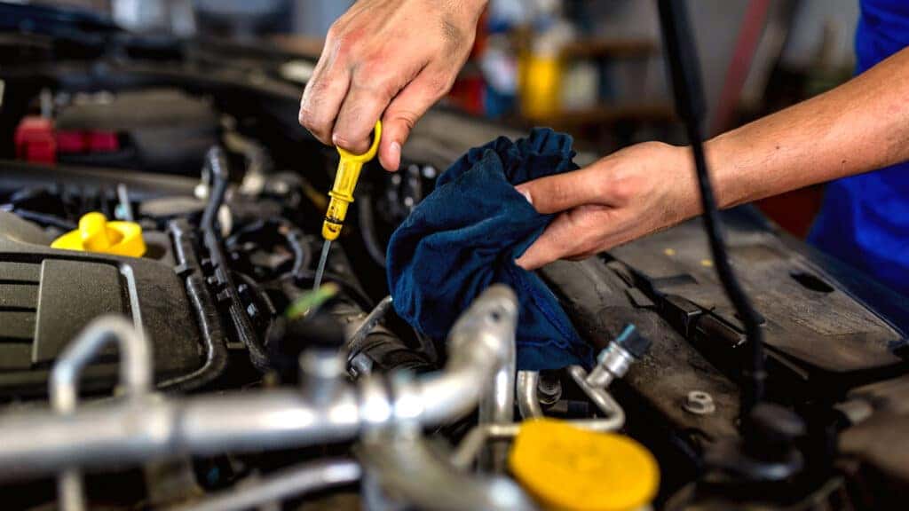 Technician checking engine oil level