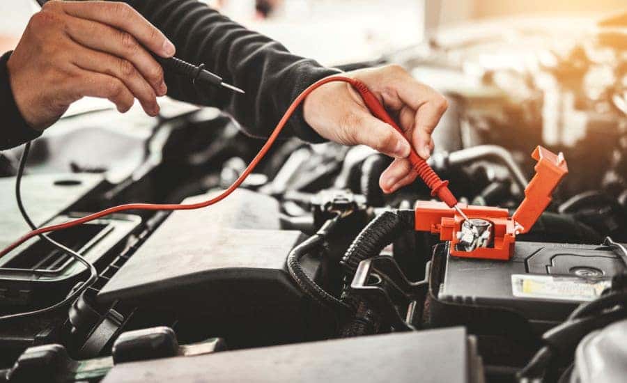 A technician testing a vehicle's battery