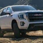 White GMC Yukon SUV Dirt Road Green Grass
