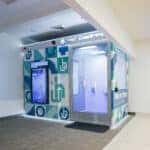 OnMed Care Station at Warren Henry Auto Group's corporate headquarters— a sleek, modern telehealth kiosk providing convenient, on-demand medical consultations for employees.