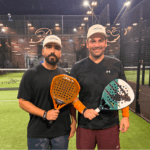 Two winners of the JLR North Dade and Reserve partnership padel tournament posing with their awards. Both winners, JLR North Dade clients, stand proudly on the court, holding their trophies with smiles, celebrating their victory in the exciting competition.