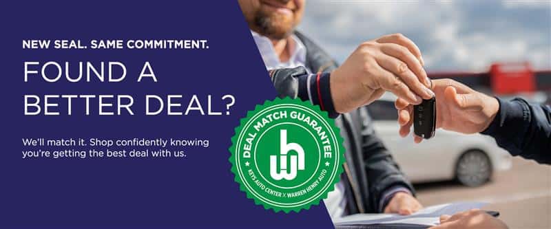 Two people exchanging car keys outdoors, with a bold text overlay that reads 'FOUND A BETTER DEAL?' and a green badge labeled 'Deal Match Guarantee - Keys Auto Center x Warren Henry Auto.' The background includes a blurred car dealership lot and a blue sky