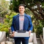 Abraham Cohen of Bugatti Broward smiles while holding a Bugatti award trophy after being named “Best Performing Brand Manager in 2024” by Bugatti Automobiles S.A.S., standing outdoors in a garden setting.