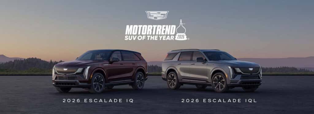 Two Cadillac Escalade IQ SUVs in black and silver parked side by side, celebrating MotorTrend’s SUV of the Year recognition.