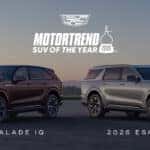 Two Cadillac Escalade IQ SUVs in black and silver parked side by side, celebrating MotorTrend’s SUV of the Year recognition.