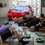 YogaJoint event attendees practicing yoga poses in front of a red vintage Lamborghini Countach inside the Lamborghini Broward showroom.