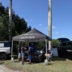 Jaguar Land Rover South Dade display at the 20th Annual Deering Seafood Festival featuring a Range Rover, Defender, service clinic tent, and festival attendees at Deering Estate.
